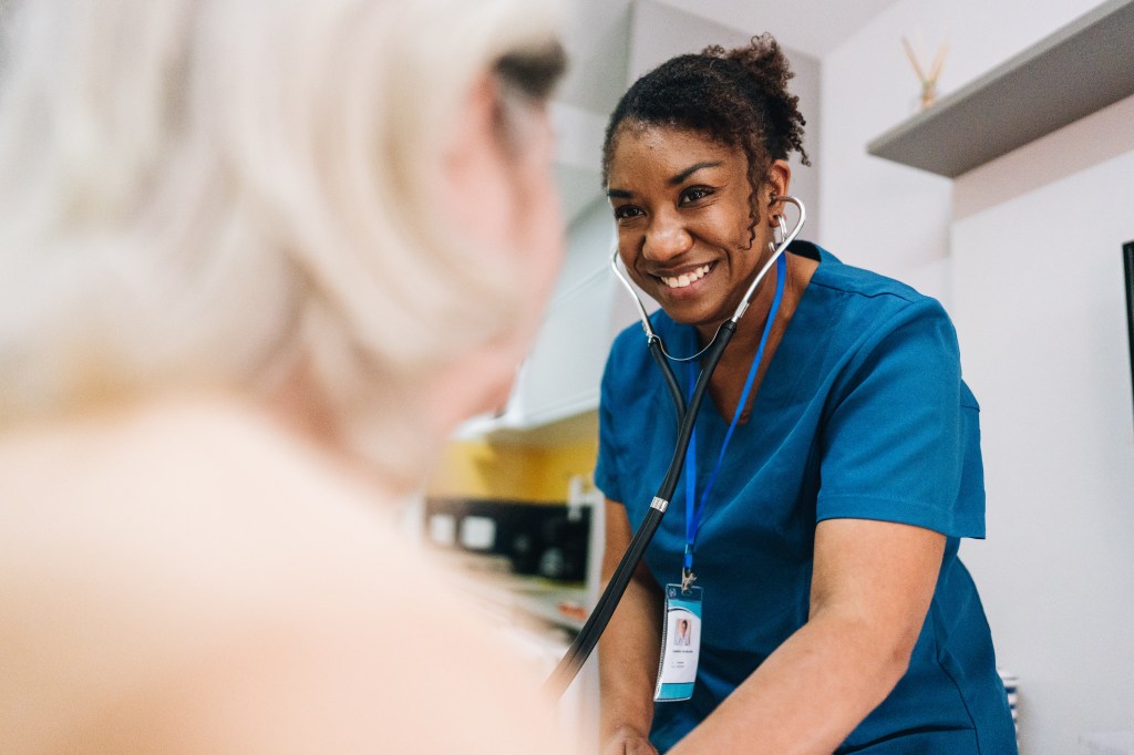 Nurse taking blood pressure of a senior woman patient at home