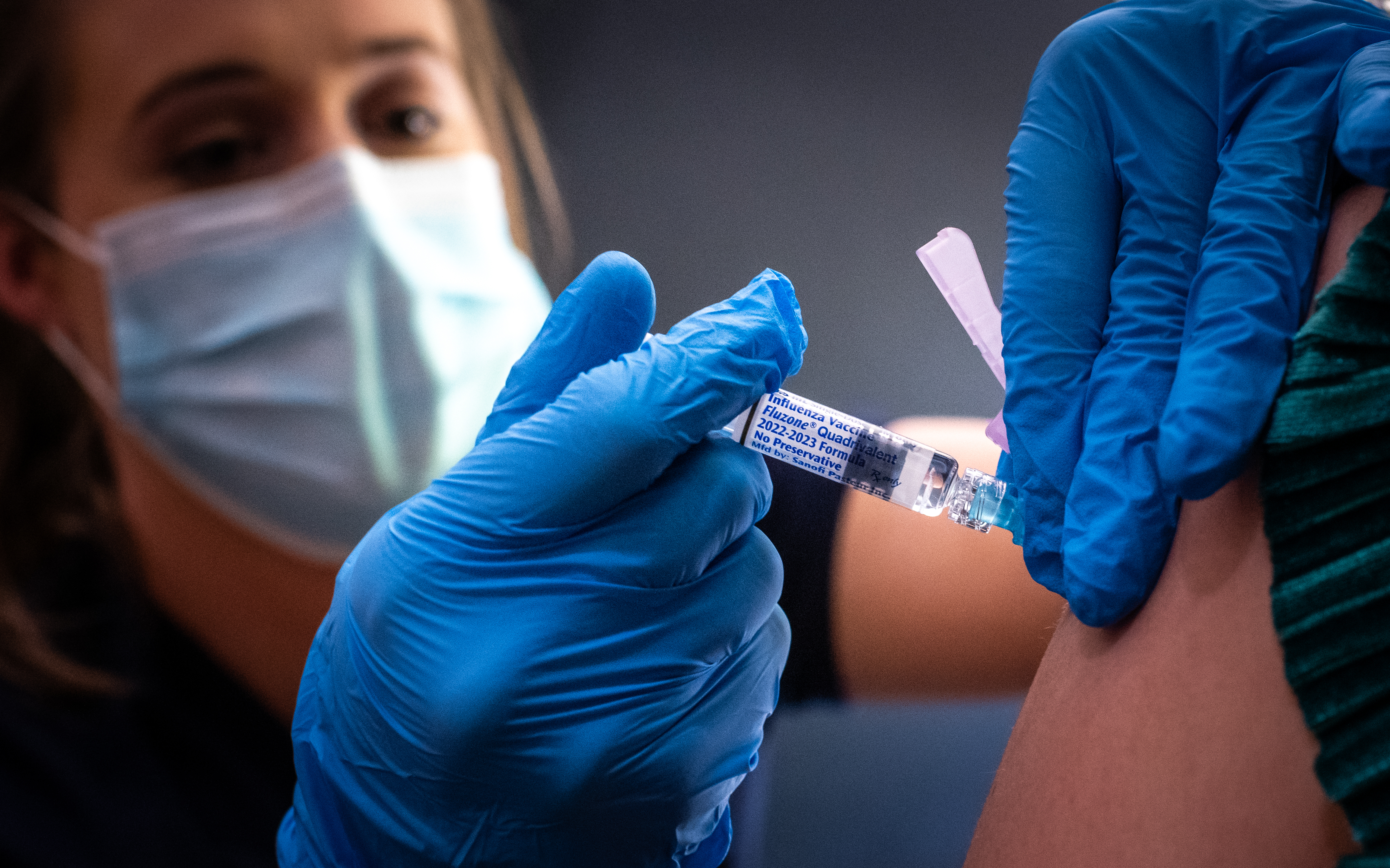 Female healthcare worker is administering the flu vaccine to an unidentified female in Spain Auditorium, October 2022.