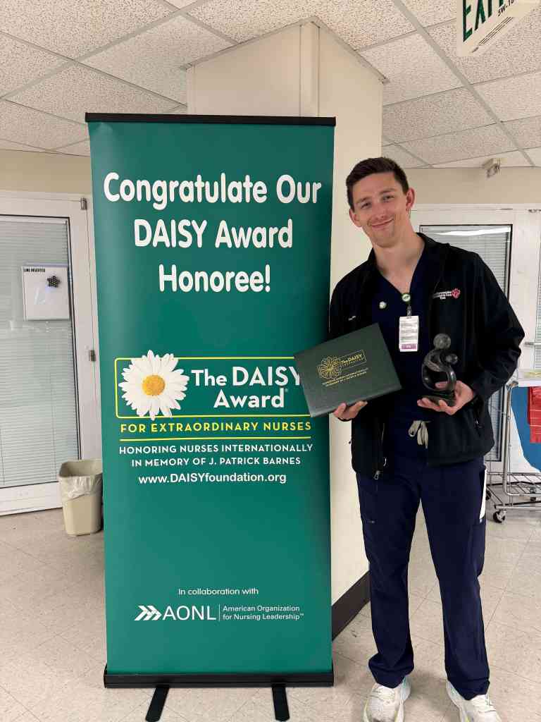 Jacob Burnham, RN stands with his DAISY award at UAB St. Vincent's Birmingham