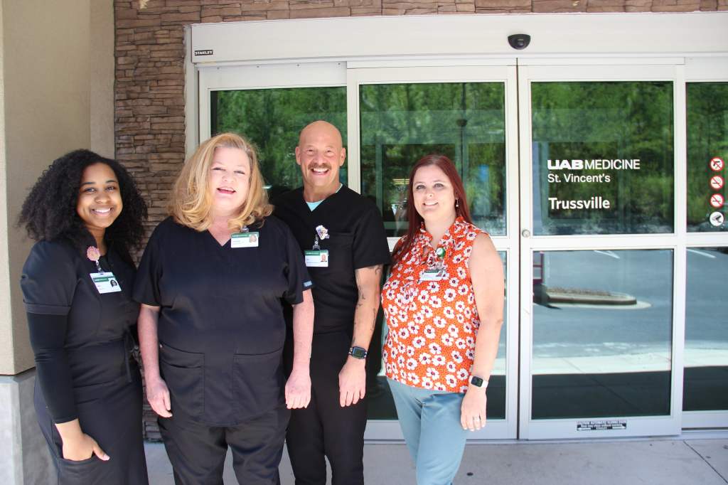 UAB Medicine St. Vincents Primary Care Trussville's Dr. Cantley and staff stand outside the front door of the facility smiling.