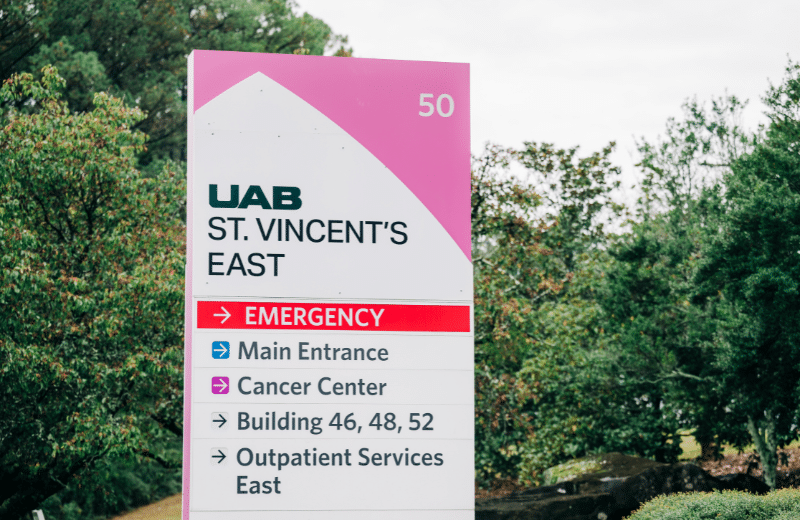 Directional sign at UAB St. Vincent’s East in Birmingham, Alabama, showing entrances for the Emergency Department, Cancer Center, and Outpatient Services at UAB Medicine’s East campus.