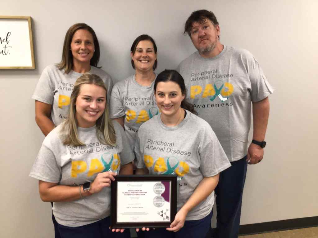 UAB St. Vincent’s Blount Wound Center care team stands together wearing Peripheral Arterial Disease Awareness shirts and holding an award plaque for Clinical Distinction and Excellence in Patient Satisfaction, recognizing high-quality wound care in Oneonta, Alabama.