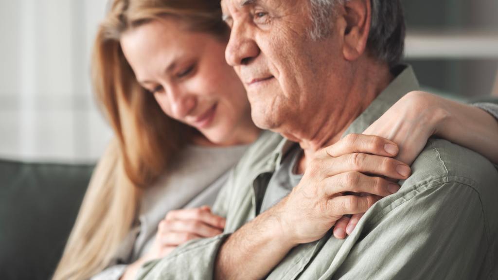 A close-up image of two individuals embracing in a supportive hug, symbolizing compassion, connection and emotional support during times of grief.