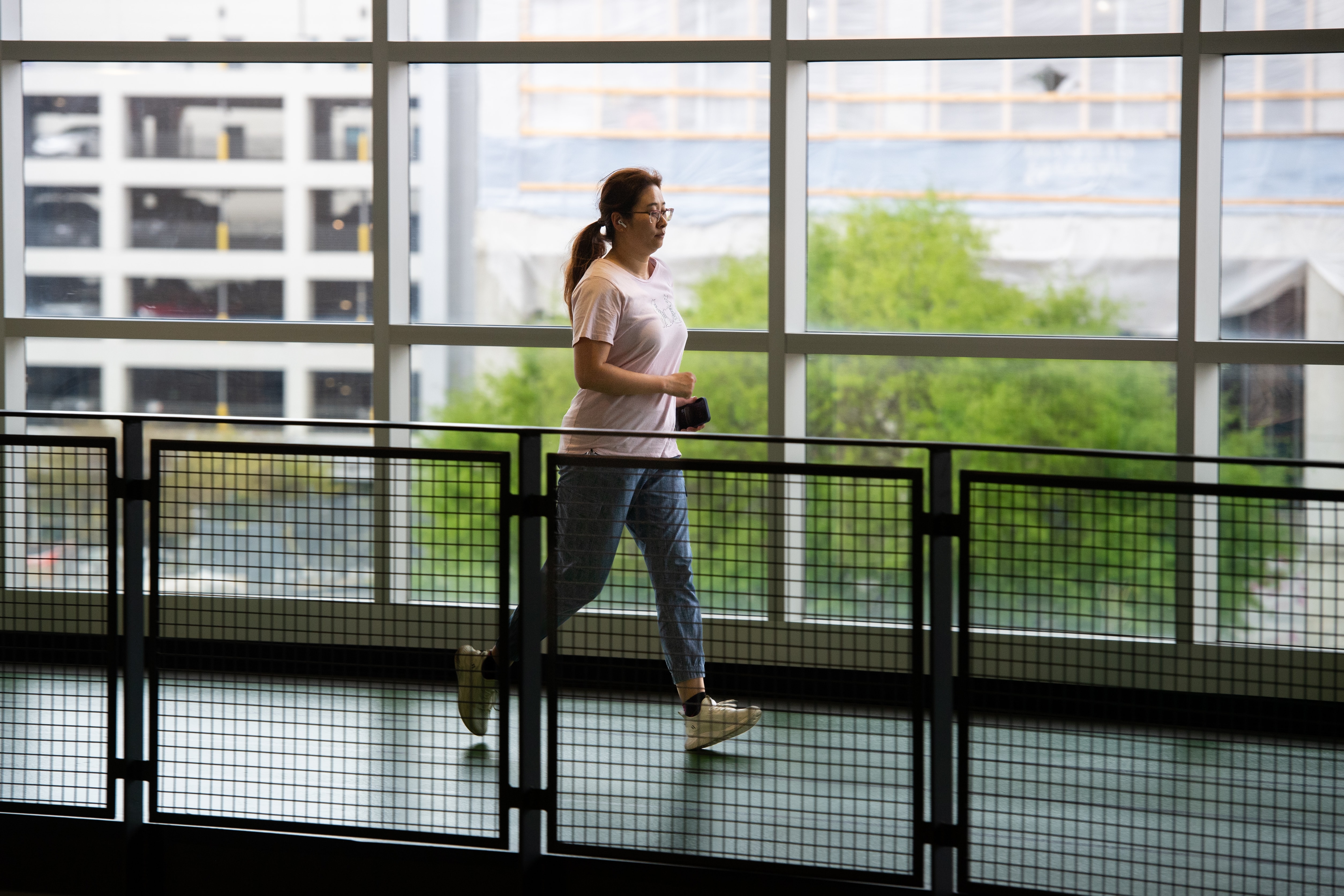 Adult walking on an indoor walking track at UAB Recreation Center with large windows overlooking Birmingham, Alabama