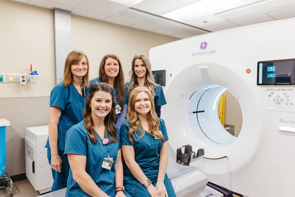 Care team at UAB St. Vincent's Chilton stand in front of CT scanning machine that can perform scans on entire organs in a short amount of time.