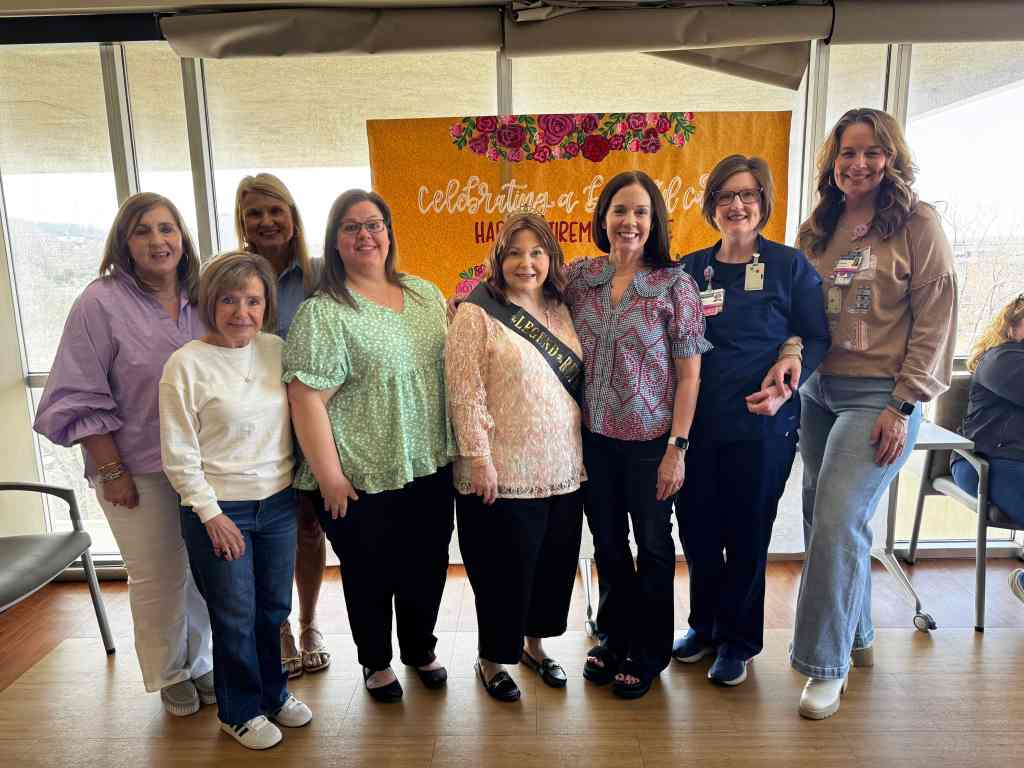 Susie Hooks stands with her coworkers at UAB St. Vincent's Birmingham. She wears a retirement sash celebrating her 46 year career as a labor and delivery nurse.