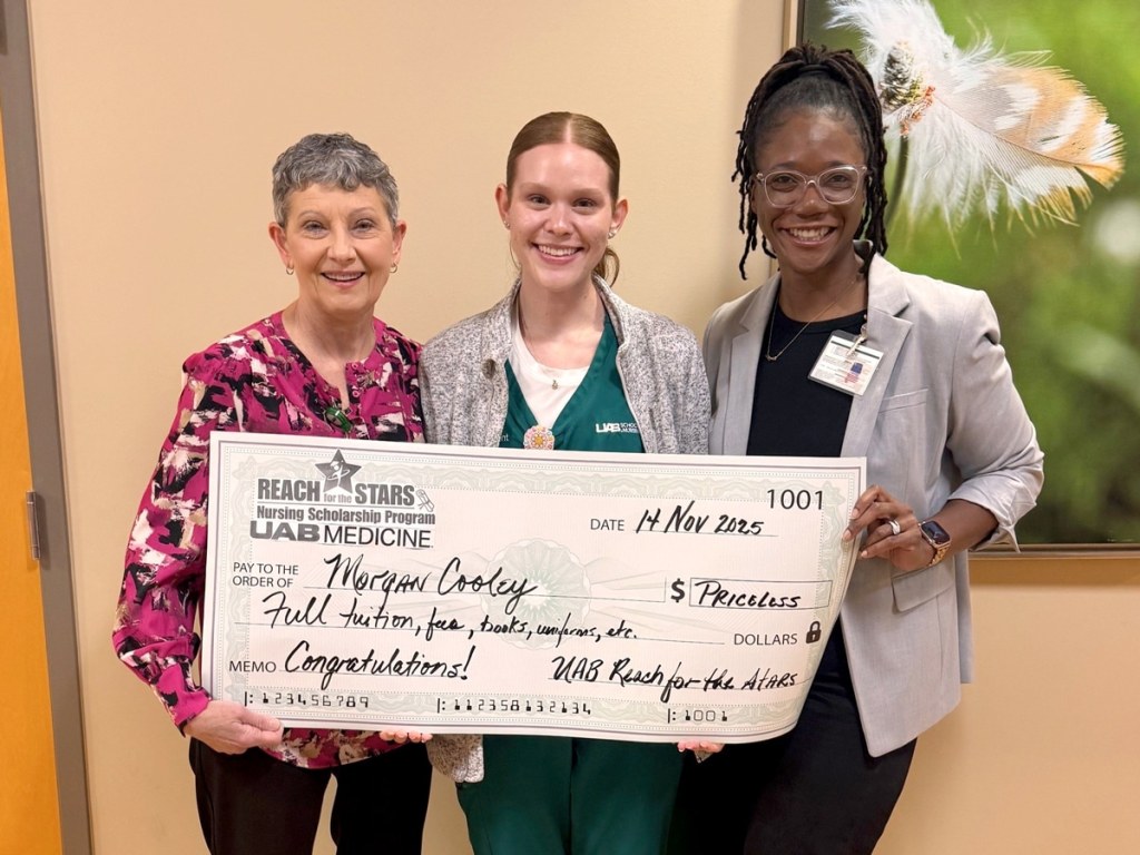 Morgan Cooley, one of the five scholarship recipients for the spring semester, stands with two UAB colleagues holding a check for full tuition for nursing school at UAB.