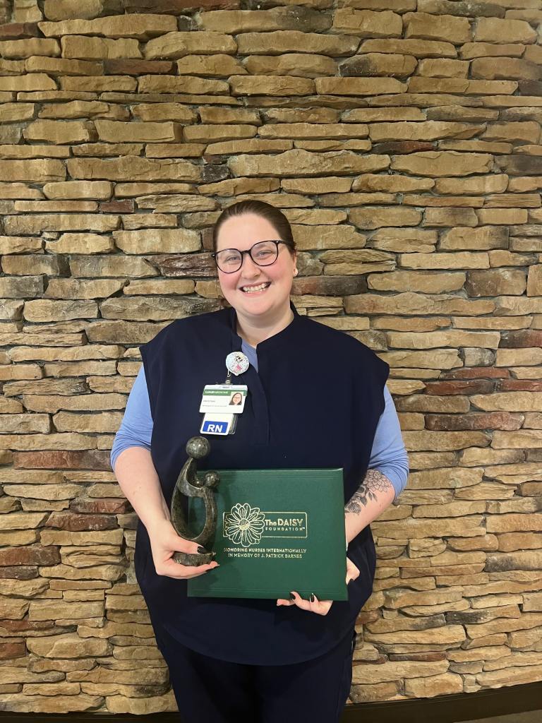 Kristina Victory, RN stands with her DAISY Award at UAB St. Vincent's Chilton