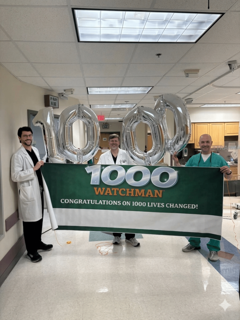 Cardiovascular team stands in the hallway of UAB St. Vincent's East with balloons and a banner that reads "Congratulations on 1000 lives changed"