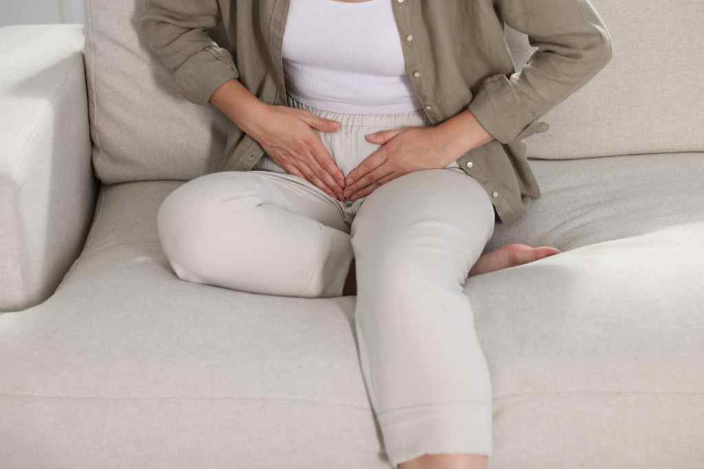 woman sitting on the couch experiencing abdominal pressure from urinary incontinence
