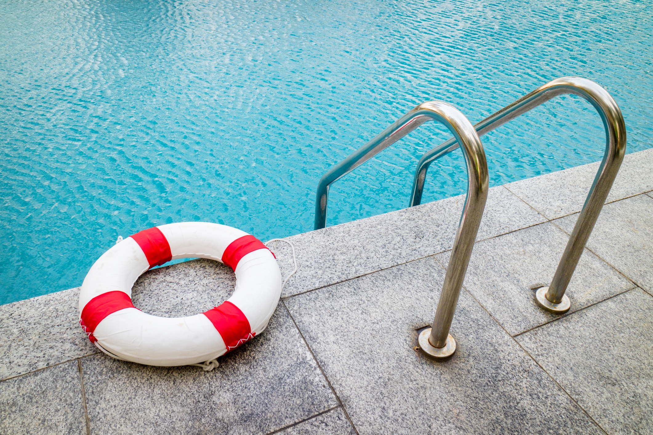 circle inflatable emergency float sitting next to the stairs entering a pool of water