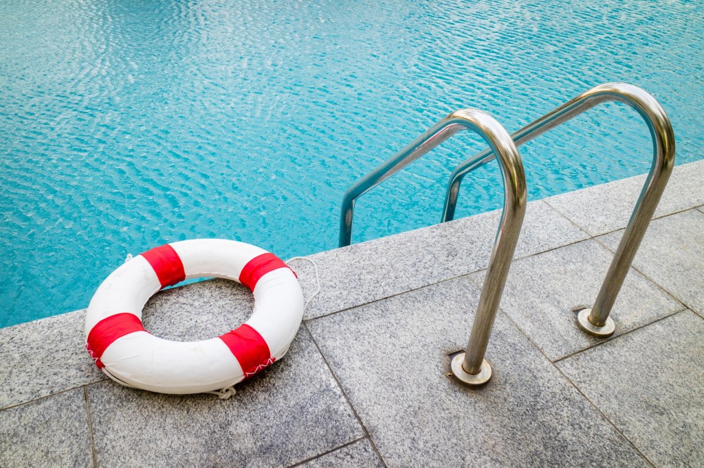 circle inflatable emergency float sitting next to the stairs entering a pool of water