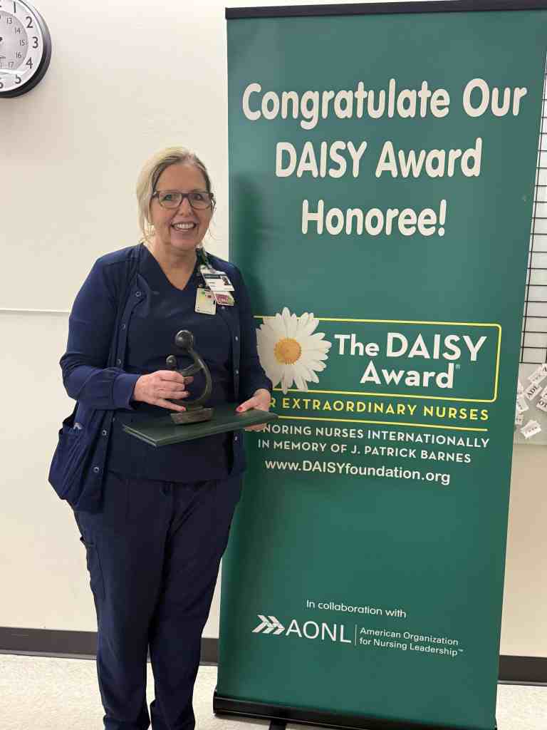 Sherrie Tinney, RN stands in UAB St. Vincent's East holding her DAISY award.