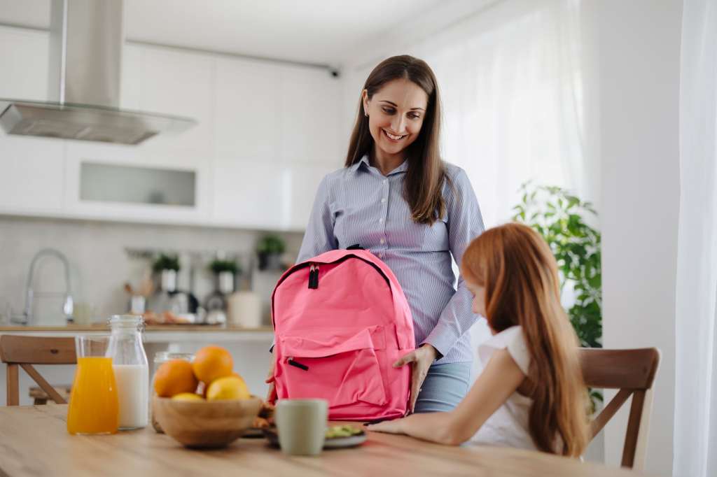 Young mom and daughter packing backpack