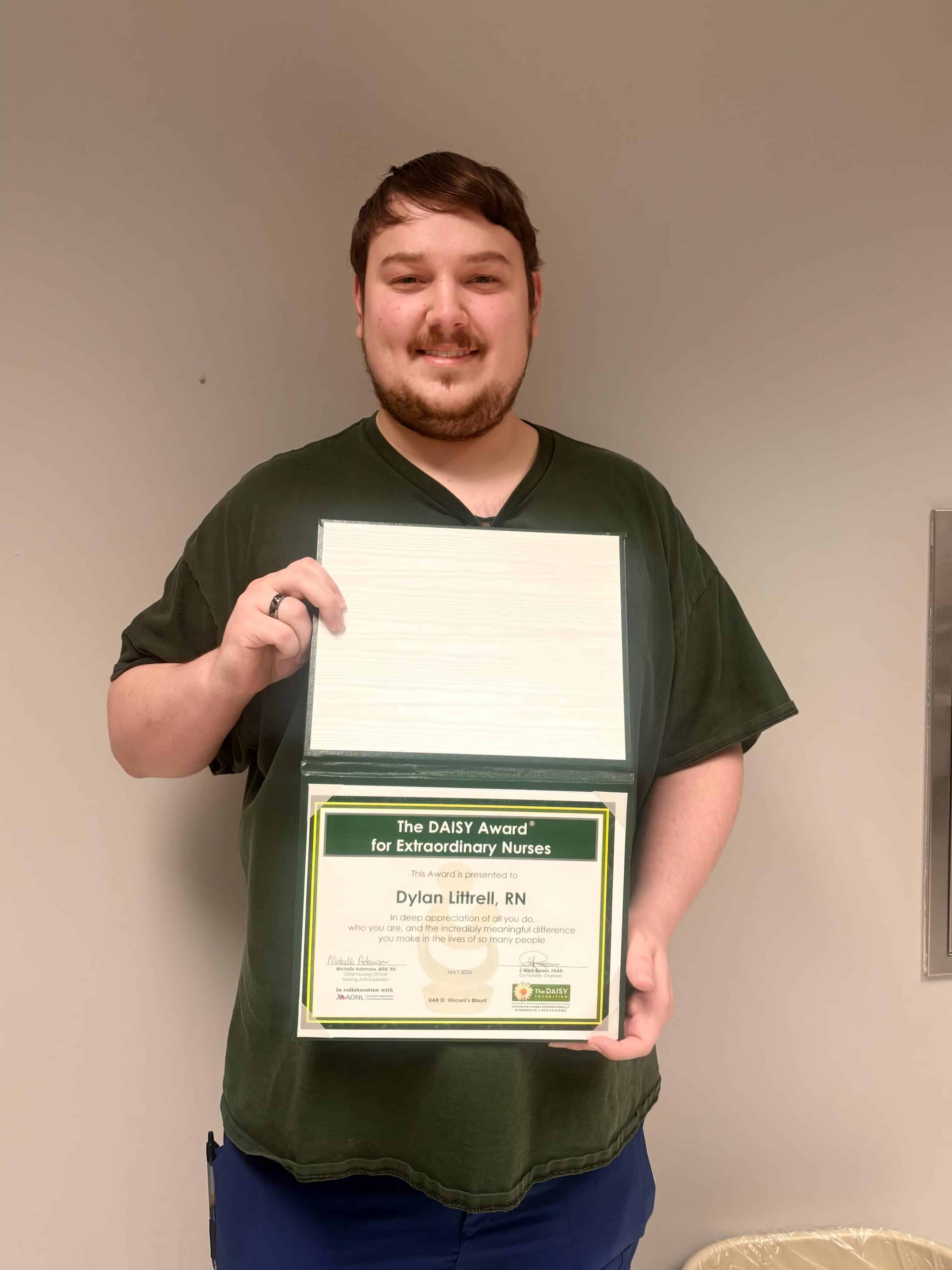 Dylan Littrell, RN standing with his DAISY award