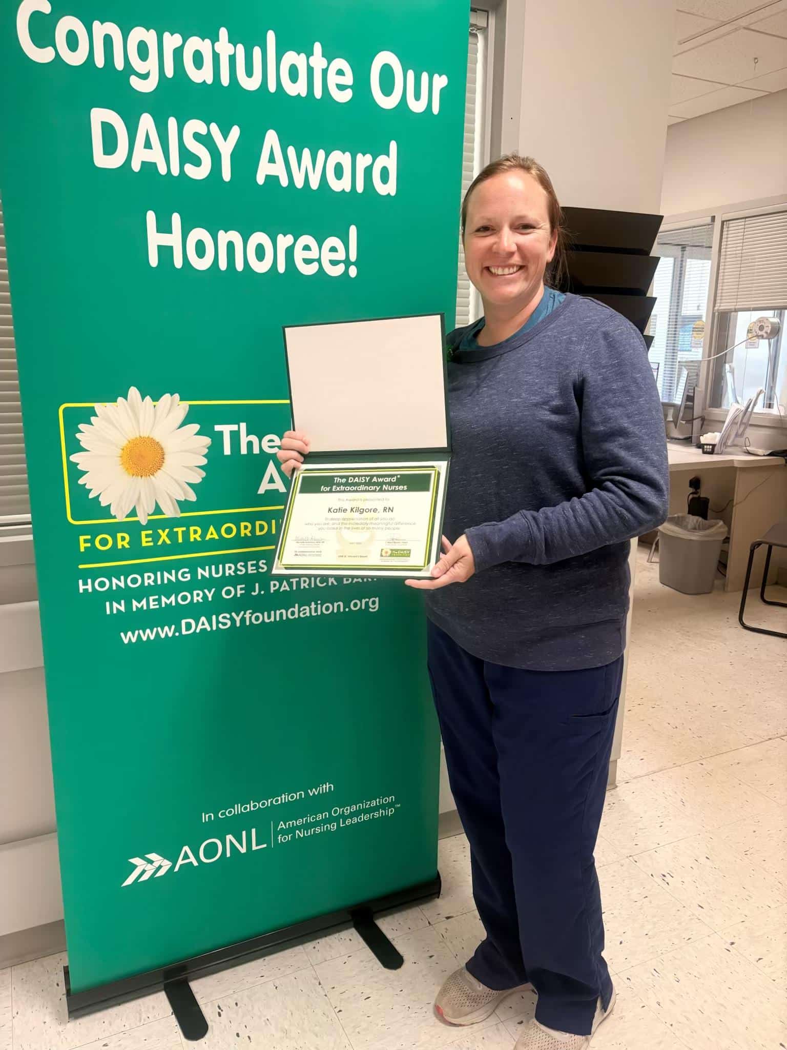 Katie Kilgore, RN stands holding her DAISY Award